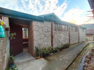 una casa con una pared de piedra y algunas plantas en Acai's Transient House, en Sagada