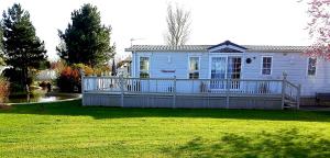 a white house with a large deck in a yard at Sunrise Holidays Skegness - Diamond in Skegness