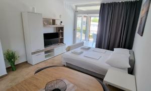 a white room with a bed and a television at Apartmani Sunce i More in Premantura