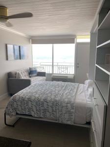 sypialnia z łóżkiem, kanapą i oknem w obiekcie Sugar Sands - Ocean front at Symphony Beach Club ! w mieście Ormond Beach