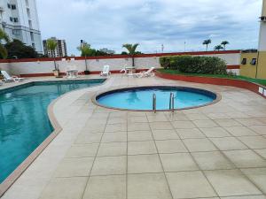a swimming pool with chairs and a building at Suíte Funcional Independente - Via Park Flat Service - Campos dos Goytacazes in Campos dos Goytacazes
