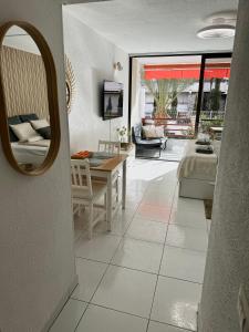 a living room with a table and a mirror at Olympia Palmalicious Apartment in Playa de las Americas