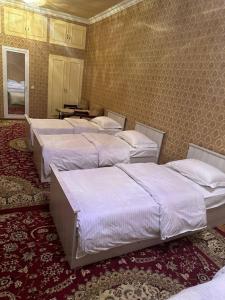 uma fila de camas num quarto com uma parede em Aisha Guest House em Samarkand