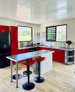 une cuisine avec des placards rouges et un comptoir avec des tabourets dans l'établissement Moorea villa neuve, vue panoramique - Painapo Lodge Ho'e, à Paopao