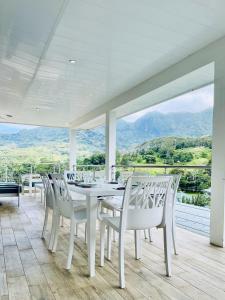 Moorea villa neuve, vue panoramique - Painapo Lodge Ho'e في Paopao: غرفة طعام بيضاء مع طاولة وكراسي بيضاء