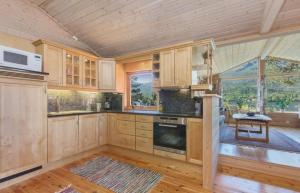 una cocina con armarios de madera y una gran ventana en Flott hytte med panoramautsikt og privat strand, en Stavang