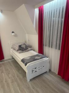 a bedroom with a white bed and red curtains at Tatrzański Domek & SPA in Poronin