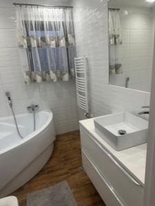 a white bathroom with a tub and a sink at Tatrzański Domek & SPA in Poronin