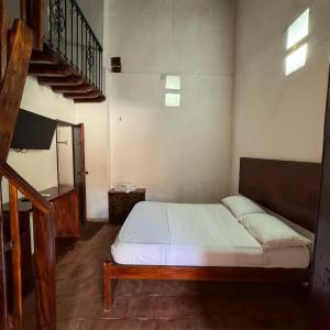 a small bedroom with a bed and a staircase at HOTEL CASA ALEMAN EN MOMPOX CON PARQUEADERO Y PISCINA CENTRO HISTORICOo in Mompós