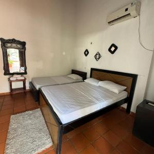 a bedroom with two beds and a window and a fan at HOTEL CASA ALEMAN EN MOMPOX CON PARQUEADERO Y PISCINA CENTRO HISTORICOo in Mompós