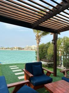 eine Terrasse mit Stühlen, einem Tisch und einer Palme in der Unterkunft فيلا بشاطئ خاص ومسبح in Durrat Al-Arus