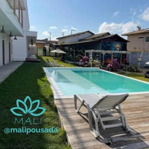 ein Swimmingpool mit zwei Liegestühlen neben einem Haus in der Unterkunft Pousada Mali in Canoa Quebrada + 21 Fotos