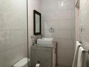 Baño blanco con lavabo y espejo en Diosamar Hotel y Suites, en Santo Domingo