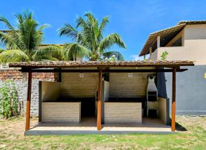 a patio with chairs under a roof next to a building at Apartamento na Praia de Guaibim in Guaibim