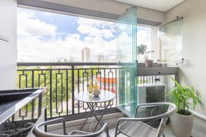 a balcony with a table and chairs and a large window at Estúdios Aconchegantes na Vila Mariana in Sao Paulo