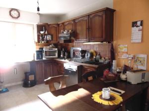 a kitchen with wooden cabinets and a table with a sunflower on the table at Maison dans un cadre de verdure in Saverne