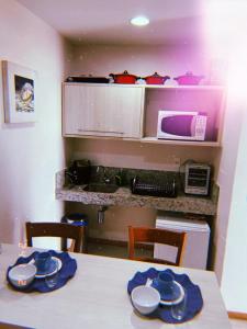 a kitchen with a table with blue plates and a microwave at Hotel Porto Marina Rede Mont Blanc in Mangaratiba