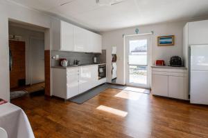 a kitchen with white cabinets and a wooden floor at casa Battilana Li Curt - Poschiavo in Prada