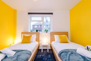 two beds in a room with yellow walls at NEW! Spacious 2-bed Apartment in Crewe by 53 Degrees Property, ideal for Business & Professionals, FREE Parking - Sleeps 6 in Crewe