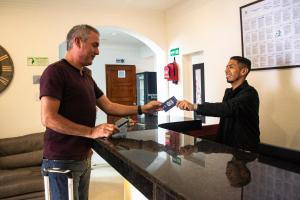 two men are standing at a counter holding cards at Hotel Casa Morada FC in Bogotá