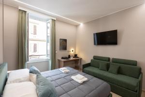 Una sala de estar con una cama, un sofá y un televisor. en IRON Luxury Rooms, en Roma