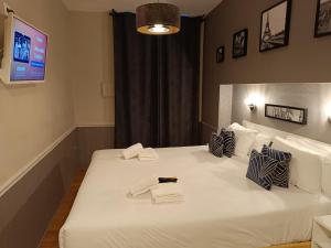 a bedroom with two beds with white sheets and a tv at H&ocirc;tel Apollo Op&eacute;ra in Paris