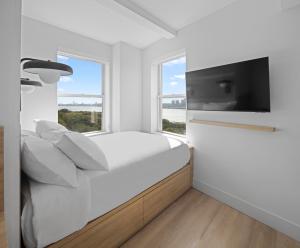 ein weißes Schlafzimmer mit einem Bett und einem großen Fenster in der Unterkunft Riverside Tower Hotel in New York