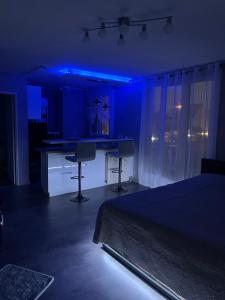 Cette chambre sombre comprend un lit et une cuisine avec des lumières bleues. dans l'établissement Love Room & Spa Jacuzzi, à Fleury-les-Aubrais