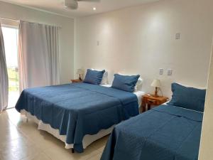 1 dormitorio con 2 camas con sábanas azules y ventana en Pousada Alto da Serra, en Conservatória