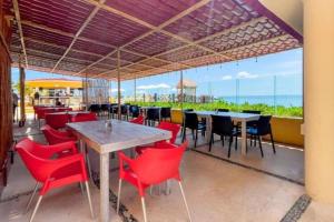 ein Restaurant mit roten Stühlen, Tischen und Meerblick in der Unterkunft Apartamento en complejo hotelero con playa in Cancún