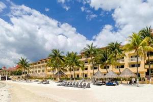 カンクンにあるApartamento en complejo hotelero con playaのヤシの木と椅子が並ぶビーチ沿いのホテル