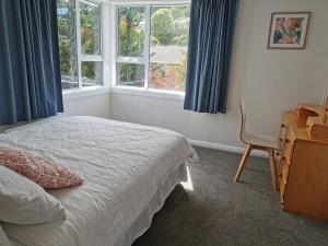 Modern home in Dunedin في دنيدن: غرفة نوم بسرير ومكتب ونافذة
