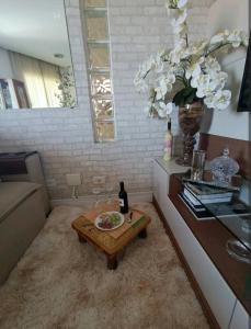 a living room with a table and a vase of flowers at Aconchego 1 in São Roque