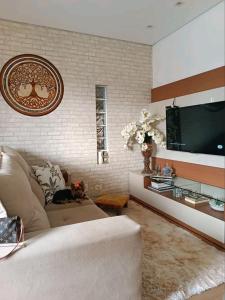 sala de estar con sofá y TV de pantalla plana en Aconchego, en São Roque