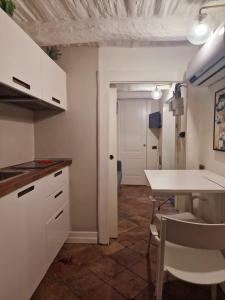 cocina con armarios blancos, mesa y sillas en LEONARDO Loft NAPLES, en Nápoles