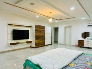 a living room with a flat screen tv and a bed at Luxury Villa within Abuja Sanctuary in Abuja