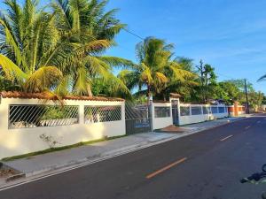 a street with palm trees and a white fence at Casa marudá in Marapanim