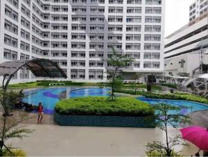 a large building with a large pool in front of it at LD Cozy 1BR Grace Residences, Taguig near BGC in Manila