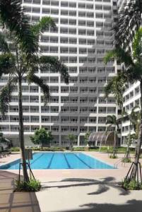 a large building with a swimming pool and palm trees at LD Cozy 1BR Grace Residences, Taguig near BGC in Manila