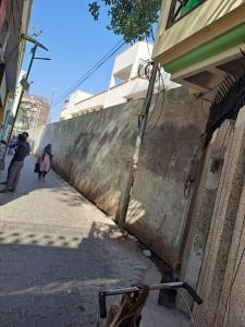 dos personas caminando por una calle junto a una pared en Hotel Happy Home en Alīgarh