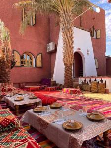 Habitación con 2 mesas y palmeras en Dar El Hakim, le petit hôtel de Timimoun en Timmoun