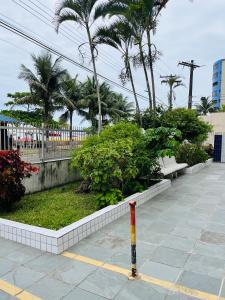 a parking lot with palm trees and a bench at Apartamento para alugar in Mongaguá