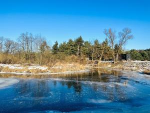 a river with snow and trees in the background at Heaven Reset & Spa - Domek nad rzeka in Korczew