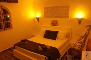 1 dormitorio con 1 cama blanca y 2 toallas en Dar El Hakim, le petit hôtel de Timimoun en Timmoun