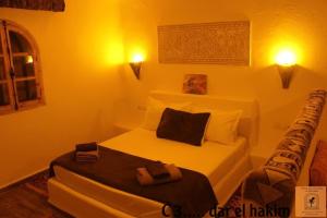 a bedroom with a white bed with two towels on it at Dar El Hakim, le petit hôtel de Timimoun in Timimoun