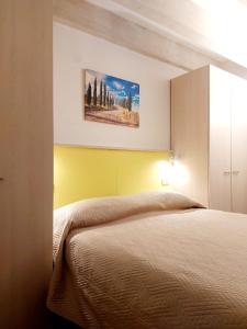 1 dormitorio con 1 cama y una pintura en la pared en La casa di Elvira2, en Castelnuovo Berardenga