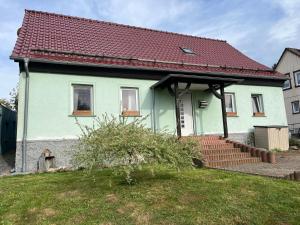 a green house with a red roof and stairs at Ferienhaus Auszeit Harz Braunlage/Hohegeiß in Braunlage