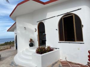 VILLA SIEMPRE DOMINGO في Tecuán: منزل أبيض مع سلالم أمام المحيط