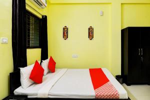 a bedroom with a bed with red and white pillows at OYO Flagship Sri Balaji Guest House in Bhubaneshwar