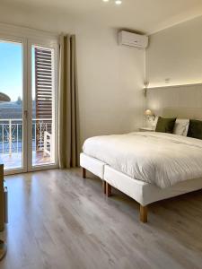 a white bedroom with a bed and a balcony at Villa Pensione Mercedes in Sirmione